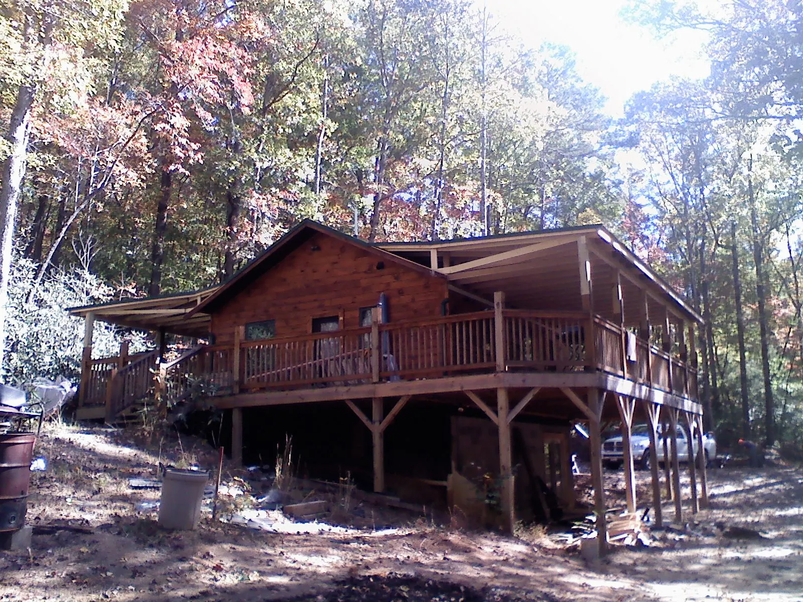 Log cabin with a wraparound porch and metal roof in the fall in Deer Park