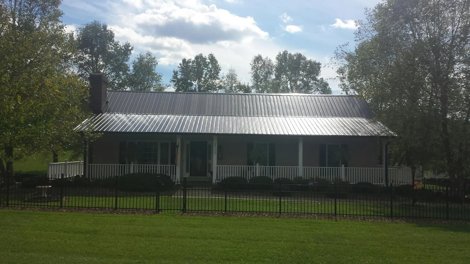 Gray metal roof on a brick ranch with a full width front porch — Gutter Guard Installation work by our crew in Deer Park